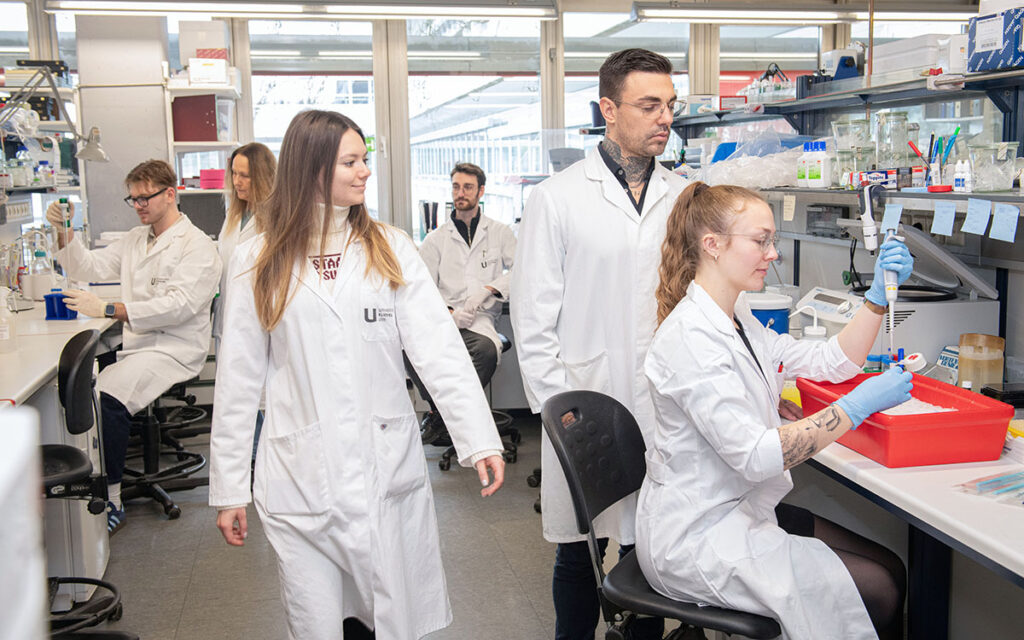 Mitarbeiterinnen im Labor, eine Mitarbeiterin hantiert mit einer Pipette